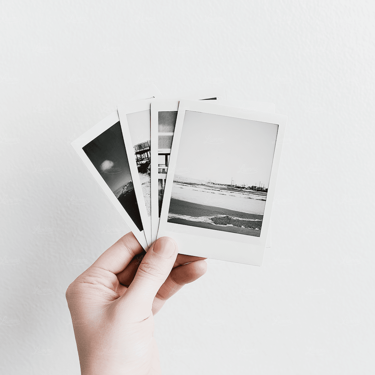 A hand holding a set of black and white photographs during research